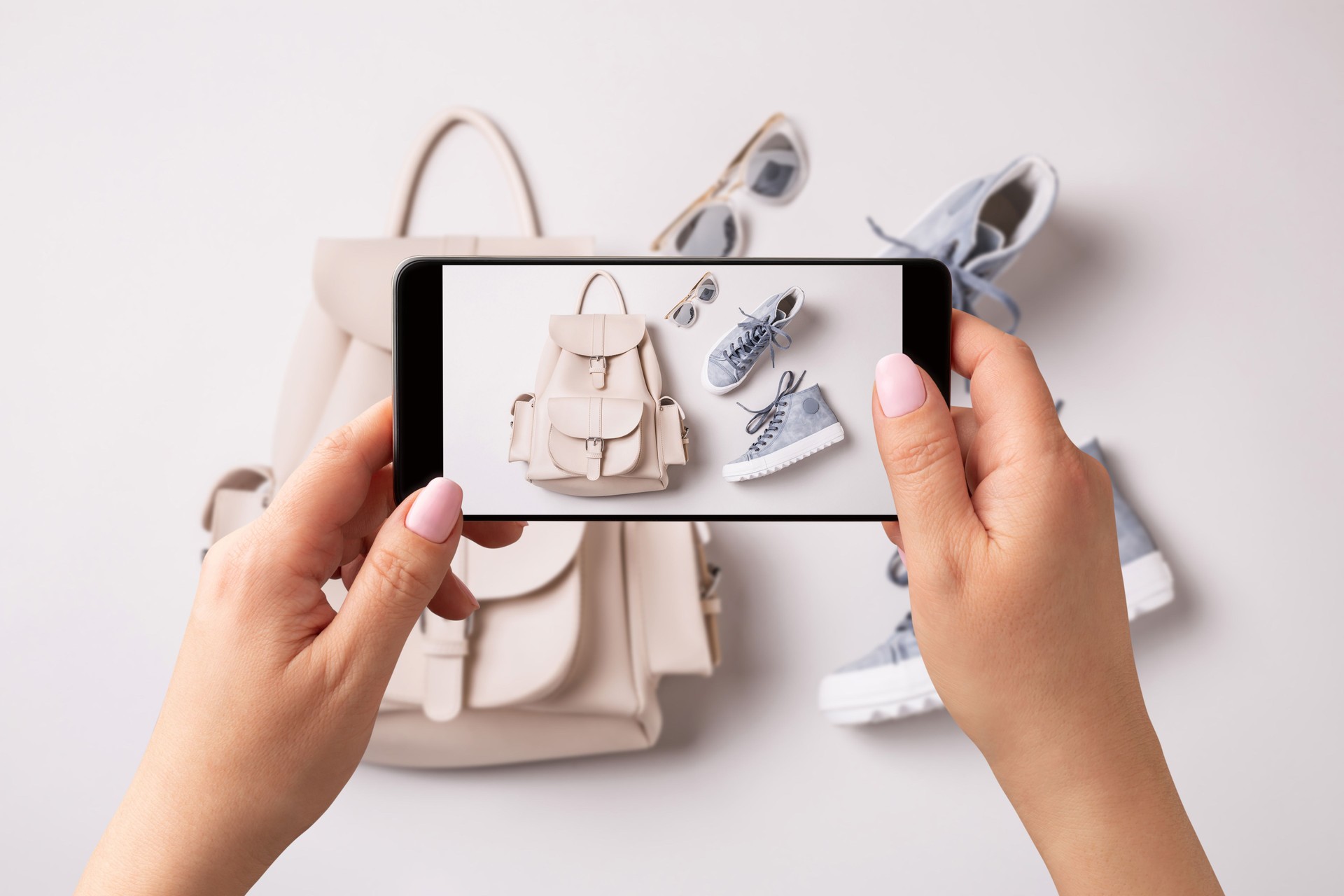 Woman taking photo of white backpack and blue sneakers with smartphone. Influencer and social media.